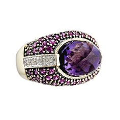 Color your world! This vintage Le Vian ring is a stunning 14K gold beauty. The ring features a high domed, checkerboard amethyst in an oval shape that is horizontally set. The face of the ring is paved with 70 rich pink rubies, and there is a stripe of 5 diamonds set in white gold on each side. The back of this weighty ring is highly polished, and it is comfortable to wear.  Vintage: 1990s  Size: 7 Materials:  Solid 14K Gold, Amethyst, Rubies, Diamonds Marked: 14K, Le Vian, Le Vian maker's mark Amethyst: high dome, checkerboard cut, approx. 15mm x 10mm x 10mm 70 Rubies: round faceted, approx. 2mm 10 Diamonds: round brilliant cut, approx. 1.5mm each, approx. .15 ctw, avg. SI-2 clarity Width North to South: 9/16" Width East to West: 7/8" Stands Off Finger: just over 3/8" Shank Width: just ov Levian Rings, Ladies Silver Rings, Rubies And Diamonds, Gold Beauty, Le Vian, Amethyst Jewelry, Purple Stones, Ruby Diamond, Maker's Mark