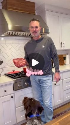 a man standing next to a dog in a kitchen