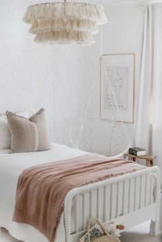 a bedroom with a bed, hanging chair and pictures on the wall above it is decorated in neutral colors