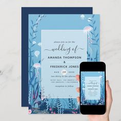 a person holding up a cell phone in front of a wedding card with jellyfish on it