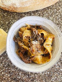 a white bowl filled with pasta next to a loaf of bread