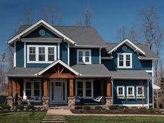 a blue house with white trim and two story windows on the front, and an attached porch