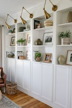 a living room filled with lots of white bookshelves covered in pictures and plants