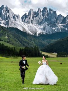 the bride and groom are walking in front of mountains