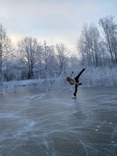 a person is skating on an ice covered pond with trees in the background and snow flakes all around