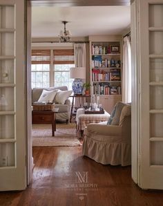 an open door leading to a living room with furniture and bookshelves in it