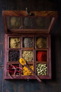 an open wooden box filled with different types of spices