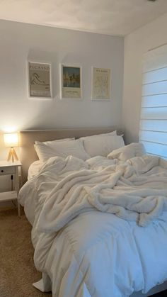 an unmade bed with white sheets and blankets on it in the corner of a room