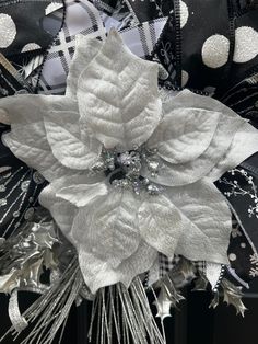 a black and white poinsettia decorated with silver foil, beads and ribbon