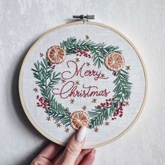 a hand embroidered christmas ornament with oranges and pine cones in the center