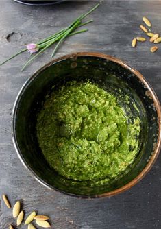 a bowl filled with pesto next to some flowers