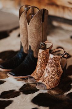 two pairs of cowboy boots sitting on top of a cow print rug