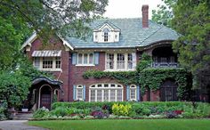 a large brick house with ivy growing all over it's roof and windows on the front