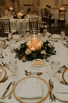 the table is set with candles, plates and silverware for an elegant wedding reception