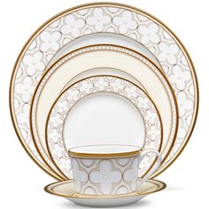 the white and gold dinnerware is set with an elegant pattern on it, along with matching dishes