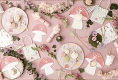 a table topped with lots of pink and white plates covered in food next to flowers