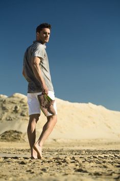 a man standing on top of a sandy beach holding a frisbee in his hand