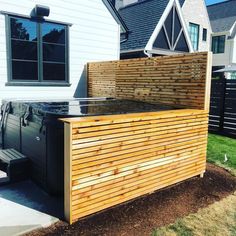 an outdoor hot tub with wooden slats on the side and grass in front of it