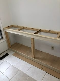 a wooden shelf sitting in the corner of a room with tile flooring and white walls