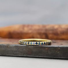 a yellow gold band with blue and white diamonds on the edge of a piece of wood