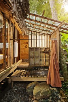 an outdoor shower in the woods with rocks and plants around it, next to a bed