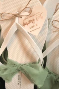 two pairs of white and green flip flops with bows tied around the toes, sitting next to each other