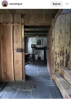 an open door leading to a room with wooden walls and stairs in front of a table