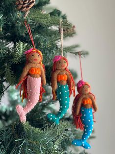 three little mermaid ornaments hanging from a christmas tree