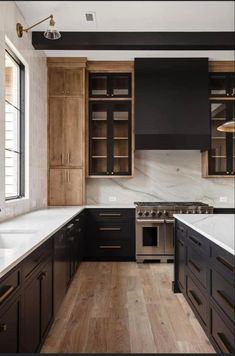 a kitchen with black cabinets and white counter tops, wood flooring and an oven