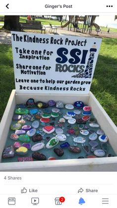 a box filled with lots of buttons sitting on top of a grass covered field next to a sign