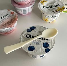 three yogurt cups with spoons on the table