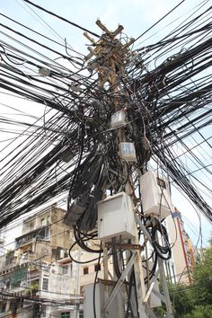 an electric pole with many wires and electrical equipment on it's sides in front of a building