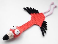 a crocheted flamingo ornament hanging on a white wall with black and pink trim