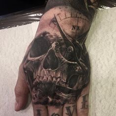 a man's hand with a skull on it and a clock in the middle