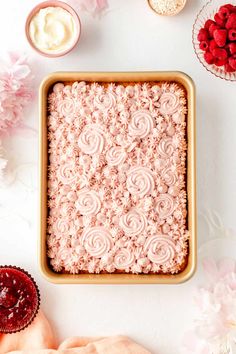 an overhead view of a cake in a pan with icing and flowers around it