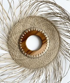 a circular object made out of straw and wood on a white surface with some dry grass