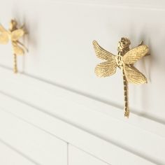 three gold dragonflys are mounted on the wall next to each other in front of a white dresser