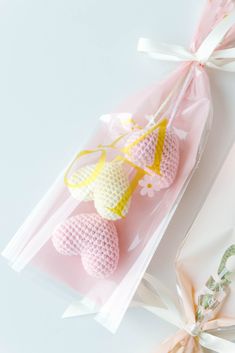 three small crocheted hearts in cellophane wrapped in pink and yellow ribbon