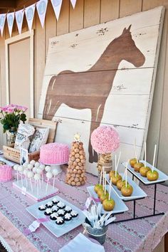 a table topped with lots of desserts next to a horse painting on the wall