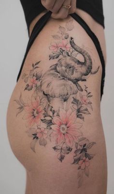 an elephant and flowers tattoo on the side of a woman's stomach