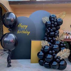 black balloons are on display in front of a happy birthday sign