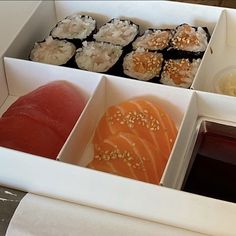 an assortment of sushi and sauces in white boxes