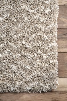 an area rug is shown with wood flooring in the background and white carpet on the ground