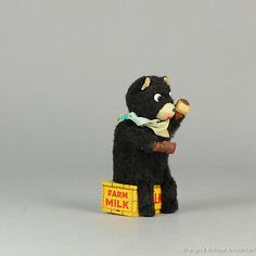 a small black bear sitting on top of a box with a bone in it's mouth