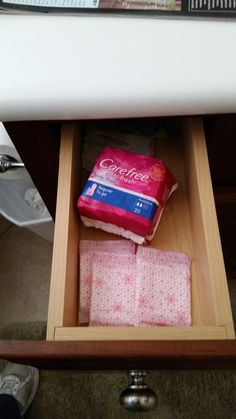 an open drawer with two pieces of toilet paper in it and one piece of pink tissue on top