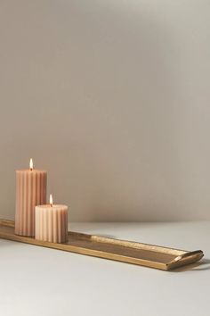 three candles sitting on a tray next to each other