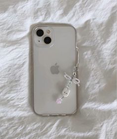 an iphone case with a keychain attached to it sitting on a white sheet