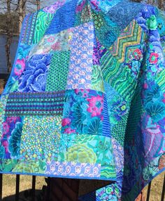 a blue and green quilt sitting on top of a fence