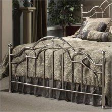 a metal bed frame in a bedroom with beige walls and carpeted flooring, along with potted plants