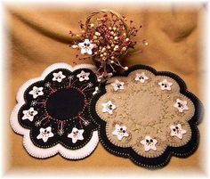 two black and white flower coasters sitting on top of a brown cloth covered table